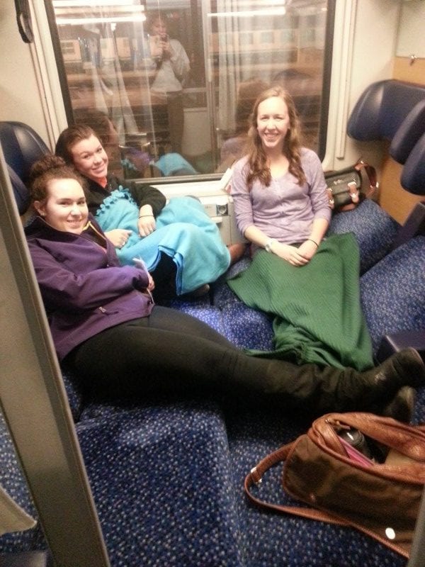 friends riding in a train car showing why you should travel when you're young