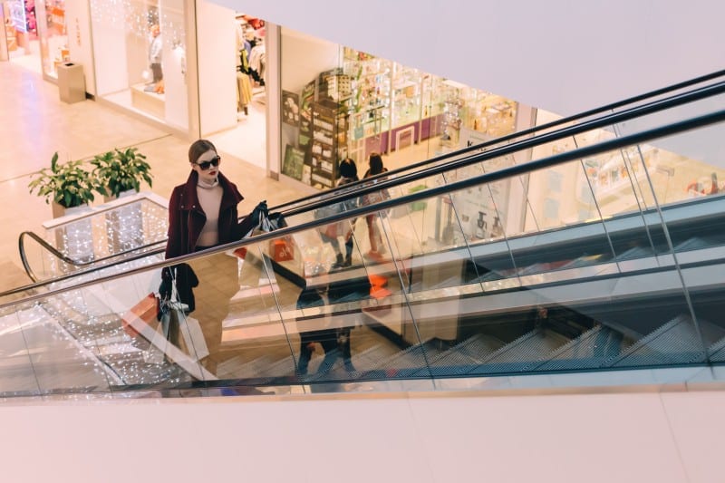 woman riding escalator in shopping mall thinking about budgeting tips